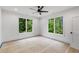 Bright bedroom features two expansive windows framing lush greenery, enhanced by a modern ceiling fan at 4125 Ashwoody Ne Trl, Brookhaven, GA 30319
