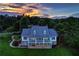 Stately home with manicured lawn, stone accents, covered porch and upper balcony against a colorful sunset backdrop at 4620 Springdale Ct, Cumming, GA 30041