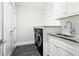 Convenient laundry room with black appliances, white cabinetry, marble counters, and black tile flooring at 4225 Wieuca Ne Rd, Atlanta, GA 30342