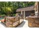 Outdoor kitchen featuring stone counters and stainless steel appliances, ideal for al fresco dining and entertaining by the pool at 4850 Lake Fjord Pass, Marietta, GA 30068