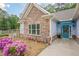 Welcoming front entry featuring stone details, a cheerful blue door and lush flowering plants at 549 Greenridge Ln, Loganville, GA 30052