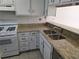 Functional kitchen featuring neutral granite countertops, white cabinetry, and stainless steel sink at 437 Saint Ives Sq, Stone Mountain, GA 30083