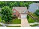 Aerial view of a well-maintained two-story home with a lush green lawn and mature trees at 1727 Shire Village Dr, Sugar Hill, GA 30518