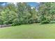 View of a lush, expansive backyard with mature trees at 1727 Shire Village Dr, Sugar Hill, GA 30518