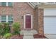 Close-up of a front door with brick surround and manicured landscaping at 1727 Shire Village Dr, Sugar Hill, GA 30518