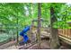 Elevated wooden playground with a blue slide in a wooded backyard at 425 Bellflower Ct, Roswell, GA 30076