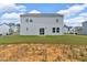 Large grassy backyard featuring a gray home, with sliding glass doors, and several other houses in the distance at 600 Tudor St, Kingston, GA 30145