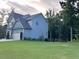 Side view of a blue two story home with a manicured yard, mature trees, and attached garage at 17 Kola Ln, Rydal, GA 30171