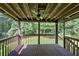 A covered back porch surrounded by trees features a ceiling fan and wooden support beams at 225 Hitchcock Dr, Villa Rica, GA 30180