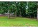 Lush green backyard with mature trees and a partial view of a fenced property at 252 Parkway Ct, Dallas, GA 30157