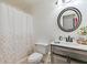 A bright bathroom featuring a toilet, vanity, mirror, shower and floral-themed shower curtain at 252 Parkway Ct, Dallas, GA 30157