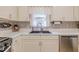 Bright kitchen featuring light-colored cabinets, a dark sink, and decorative backsplash at 252 Parkway Ct, Dallas, GA 30157