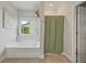 Bathroom featuring a soaking tub, a shower with a green curtain, and a large window that provides natural light at 31 Thunderhawk Ne Ln, Rydal, GA 30171