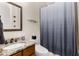 Bathroom with a granite sink top, wood cabinets, and a shower and tub combination with a decorative curtain at 5830 Caveat Ct, Suwanee, GA 30024