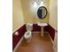 Stylish powder room featuring a pedestal sink, round mirror, and eye-catching yellow and red walls at 2517 Oak Valley Ln, Dacula, GA 30019