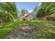 A spacious backyard with a fire pit and home in the background surrounded by mature trees at 2958 Paul Harris Rd, Dallas, GA 30157