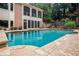 An inground pool with stone trim borders a stately home with screened porch at 7660 Treeridge Ct, Atlanta, GA 30350