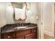 Elegant powder room featuring a dark wood vanity with marble countertop and decorative mirror at 7660 Treeridge Ct, Atlanta, GA 30350