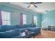 Comfortable living room featuring a plush blue sectional couch, a ceiling fan, and bright natural light at 4336 Thorngate Ln, Acworth, GA 30101