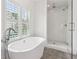 Modern bathroom featuring a soaking tub, a glass-enclosed shower, and a large window at 5971 Brundage Lane, Norcross, GA 30071