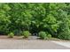 Lush landscaping featuring mature trees and greenery, and a bench at the end of a short stone walkway at 5971 Brundage Lane, Norcross, GA 30071