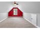 Large bonus room featuring vaulted ceilings, a ceiling fan, window, red accent wall and neutral carpeting at 320 Roland Manor Dr, Dacula, GA 30019