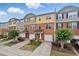 Street view of charming townhomes featuring brick, colorful siding, front garages, and well-maintained landscaping at 771 Tulip Poplar Way, Lawrenceville, GA 30044