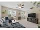 Bright living room featuring a comfortable gray couch, plush carpet, and a modern ceiling fan with ample natural light at 771 Tulip Poplar Way, Lawrenceville, GA 30044