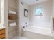 Bright bathroom featuring a soaking tub with tiled surround, open shelving, and natural light from a window at 1001 Dancing Fox Rd, Decatur, GA 30032
