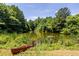A serene pond view features a rustic canoe and lush greenery, offering a tranquil natural retreat at 1001 Dancing Fox Rd, Decatur, GA 30032