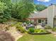An expansive backyard with a stone patio, outdoor seating, lush landscaping, and mature trees at 3633 Gilpin Ct, Lawrenceville, GA 30044