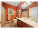 Well-lit bathroom with orange accent wall, tiled floor, and a modern vanity with marble countertop at 3633 Gilpin Ct, Lawrenceville, GA 30044