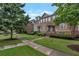 Beautiful brick townhomes with manicured lawns, mature trees, and inviting sidewalks under a blue sky at 7850 Willoughby Ct, Alpharetta, GA 30005