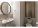 Stylish powder room with a pedestal sink, decorative mirror, and unique wallpaper at 7850 Willoughby Ct, Alpharetta, GA 30005