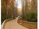 Scenic walking path through a forest with a wooden bridge railing at 7850 Willoughby Ct, Alpharetta, GA 30005