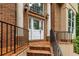 Close-up of an elegant brick entrance with a white door and black railing, framed by greenery at 815 Marshview Close, Roswell, GA 30076
