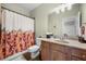 Neutral bathroom features a floral shower curtain and wood cabinets with granite countertop at 1741 Hickory Path Way, Suwanee, GA 30024