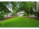 Lush backyard featuring green grass, mature trees, and other homes in the distance at 4710 Vineyard Se Ct, Smyrna, GA 30082