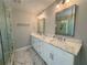 Bright bathroom featuring double vanity with marble countertop, white cabinets, and glass-enclosed shower at 703 Overlook Point, Woodstock, GA 30189