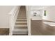 Carpeted staircase leads to a modern kitchen with white cabinets and a breakfast bar at 8225 Coldstream Dr, Fairburn, GA 30213