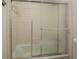 Bathroom with a tub and shower, enclosed by sliding glass doors, with classic white tiling at 115 Plantation Dr, Clarkston, GA 30021