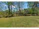 Expansive backyard with mature trees and view of a serene pond, creating a private outdoor oasis at 150 Northshore Xing, Dallas, GA 30157