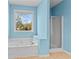 Light blue bathroom features a soaking tub, a separate shower, and a bright window at 150 Northshore Xing, Dallas, GA 30157
