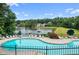 A kidney-shaped community pool with lounge chairs, umbrellas, with a lake and green space in the background at 150 Northshore Xing, Dallas, GA 30157