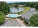 An aerial view of a kidney-shaped community pool near a lake and a clubhouse with a gray shingle roof at 150 Northshore Xing, Dallas, GA 30157