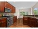 Eat-in kitchen featuring stainless steel appliances, dark wood cabinets, and granite countertops at 150 Northshore Xing, Dallas, GA 30157