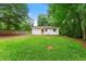 Spacious backyard with lush green grass, surrounded by mature trees, and a charming white home with a brown door at 20 Cheryl Ter, Covington, GA 30016