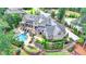 Aerial view of an estate home with stone exterior, pool, lush gardens, and manicured grounds at 4745 Cuyahoga Cv, Suwanee, GA 30024