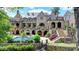 Luxury home showcasing a stunning stone facade, arched terraces, a pool, and meticulously landscaped backyard at 4745 Cuyahoga Cv, Suwanee, GA 30024