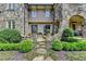 Back of a stone home, with an arched terrace, offering a view of the meticulously landscaped yard at 4745 Cuyahoga Cv, Suwanee, GA 30024